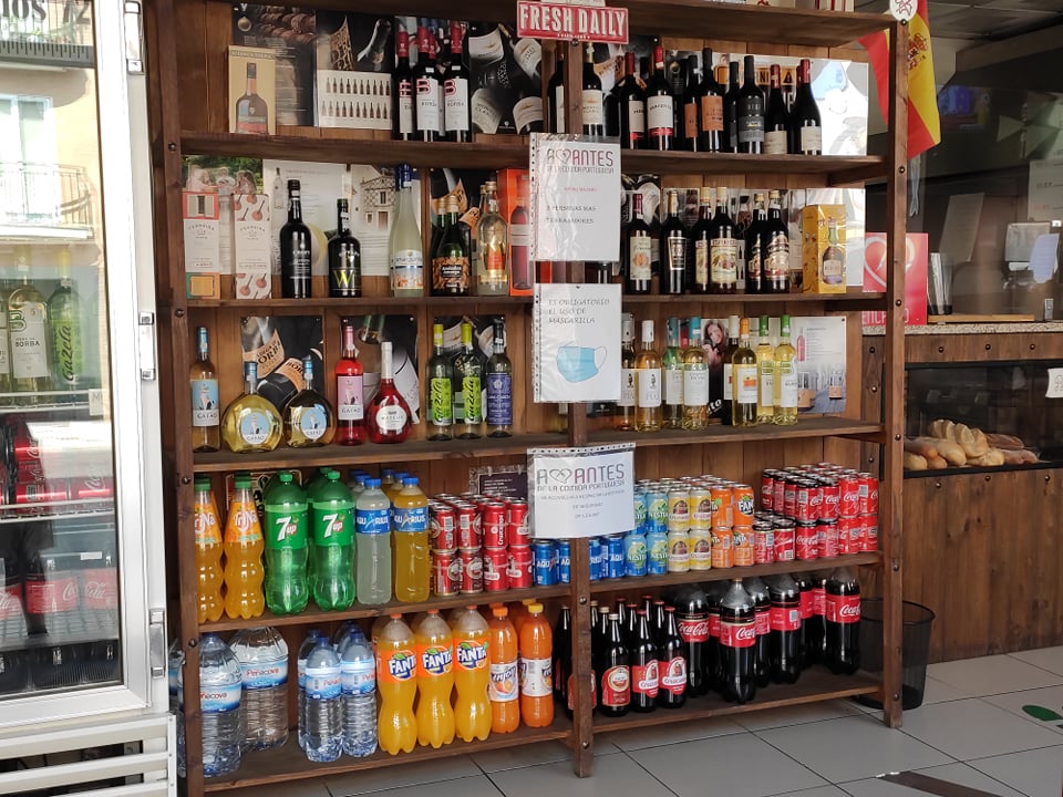 exhibición de bebidas para la venta, desde vinos en la parte superior hasta bebidas carbonatadas en botellas y latas en la parte inferior